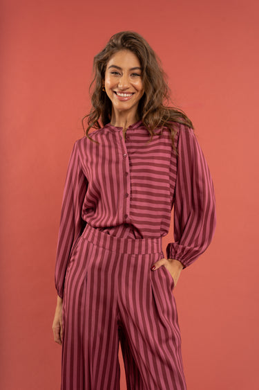 Woman wearing a maroon and pink striped outfit against a red background