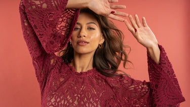 Woman wearing a burgundy lace top against a red background