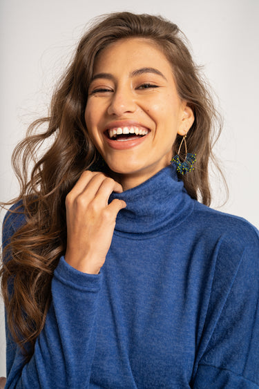 Woman wearing a blue turtleneck sweater against a white background