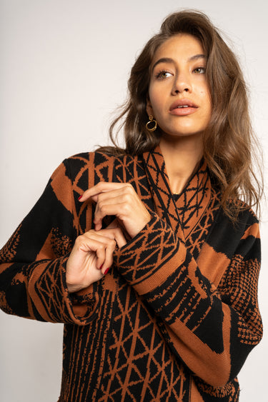 Woman wearing a patterned brown and black sweater against a white background