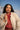 Woman wearing a beige coat over a red lace top with a mountainous background