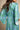 A woman wearing a blue and green tie-dye kaftan dress, shown from the back against a neutral beige background.