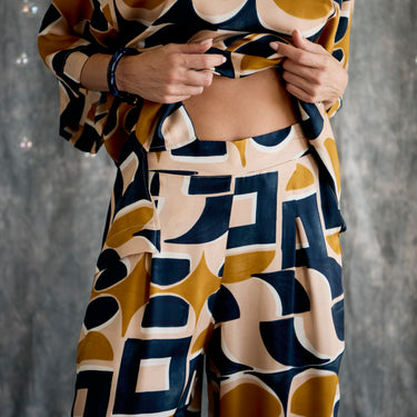 Person wearing a patterned outfit with geometric shapes against a gray background