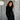 Woman wearing a black coat against a textured gray background