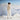 Person wearing a beige sweater and white pants standing on a snowy mountain