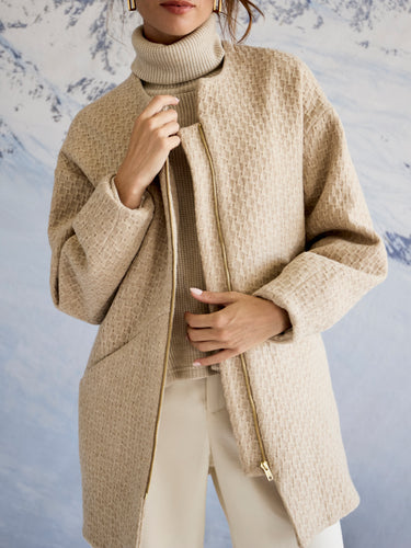 Person wearing a beige coat with a snowy mountain background