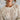 Close-up of a person wearing a white lace top with a blurred background