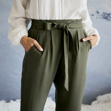 Person wearing olive green pants with a tie waist against a neutral background
