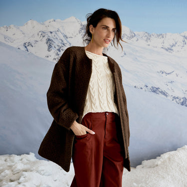 Person standing in a snowy landscape with mountains in the background