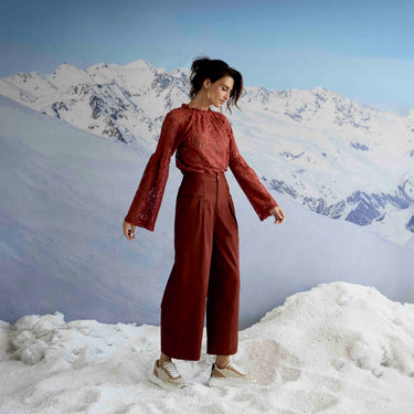 Woman in a red outfit standing in a snowy landscape with mountains in the background
