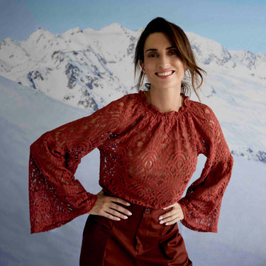 Woman wearing a red lace top with a mountainous background