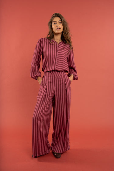 Woman wearing a maroon striped outfit against a red background