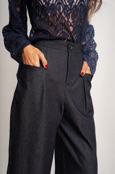 Person wearing a navy lace top and black wide-leg pants on a plain background