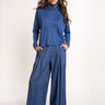 Woman wearing a blue turtleneck and striped pants on a white background