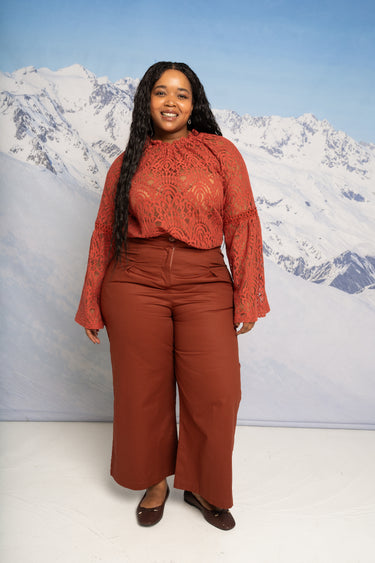Woman in a red outfit standing in front of a snowy mountain background