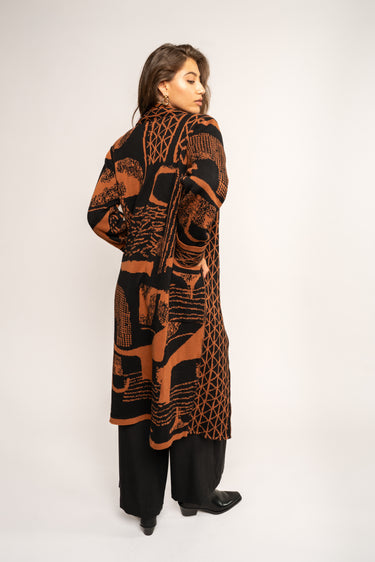 Woman wearing a long, patterned coat against a white background