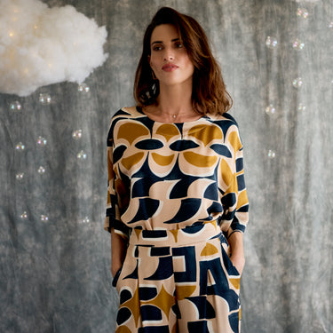 Woman wearing a patterned outfit against a textured background.