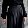 Person wearing a black outfit with wide-leg pants against a neutral background