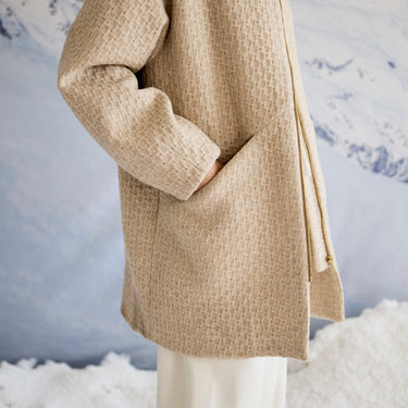 Beige textured coat on a model against a snowy landscape background