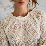 Close-up of a person wearing a white lace top with a blurred background