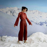 Woman in a red outfit standing in a snowy landscape with mountains in the background