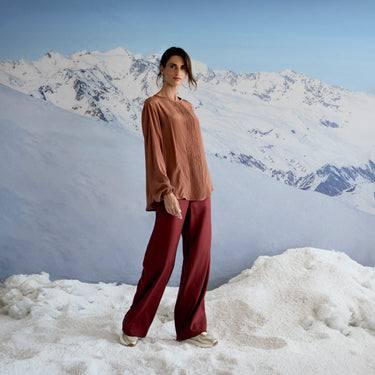 Person standing in a snowy landscape with mountains in the background