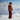 Woman in a brown top and red pants standing on a snowy mountain