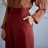 Person wearing a brown blouse and maroon skirt with a blurred background